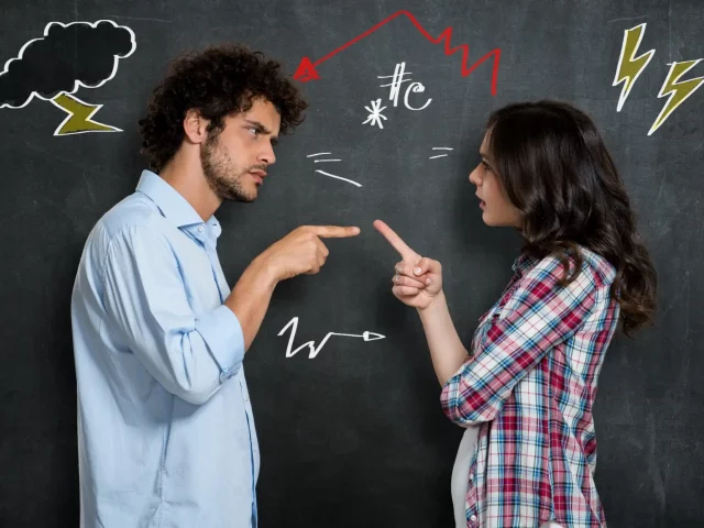 Ein Mann und eine Frau zeigen im Streit mit den Fingern aufeinander.