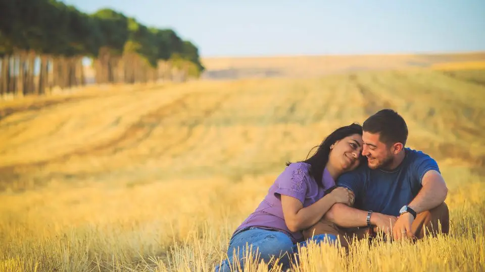 Paar sitzt vertraut in einem Feld – Symbol für vertiefende Impulse und Zusatzübungen im Bonusmaterial des Kurses Liebe ohne Kampf