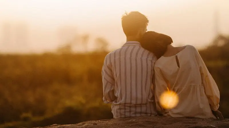 Paar lehnt sich aneinander im Sonnenuntergang – Symbol für Nähe, Verständnis und Versöhnung im Kurs Liebe ohne Kampf