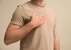 Mann legt eine Hand auf Brust und eine auf den Bauch – Symbol für Atmung und Emotionsregulation bei Wut auf den Partner